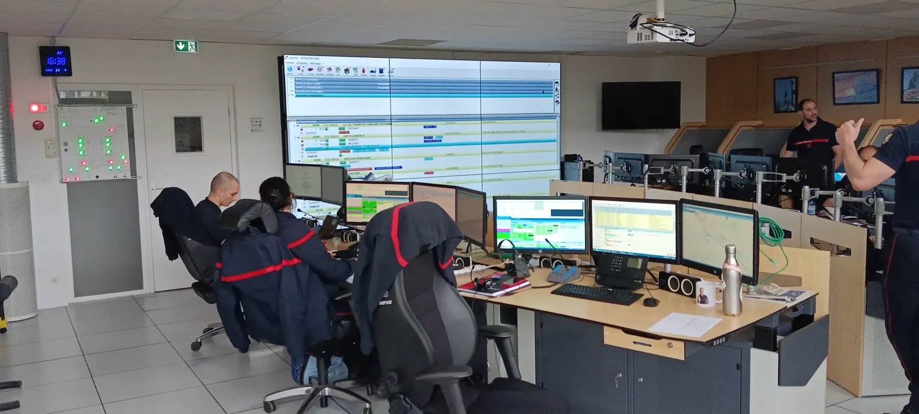Opérateurs sapeurs-pompiers en salle opérationnelle CODIS devant le mur d'images