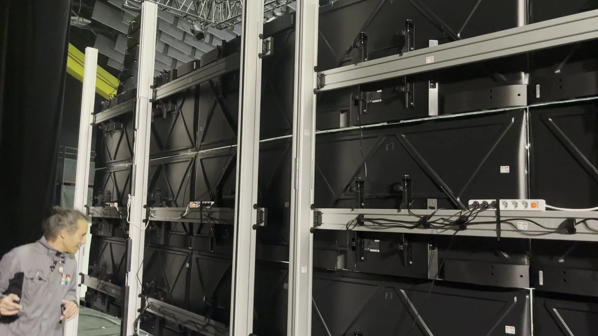 Un membre de l'équipe montre l'arrière du mur et ses supports Kimex en aluminium