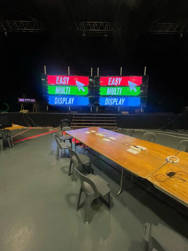 I due muri da 9 schermi affiancati davanti al grande tavolo della sala, con il logo Easy Multi Display